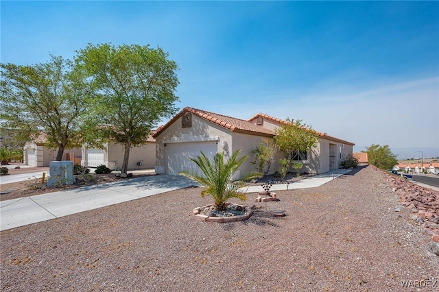 mediterranean / spanish-style house with a garage, a tiled roof, concrete driveway, and stucco siding