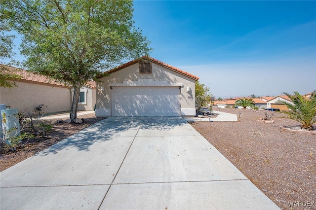 view of front of property featuring driveway, a tiled roof, an attached garage, and stucco siding