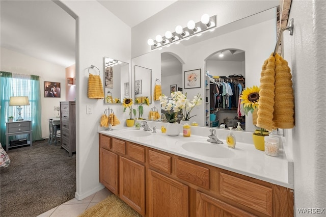 full bathroom featuring double vanity, tile patterned flooring, a walk in closet, and a sink