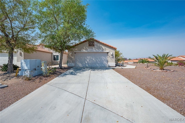 view of front facade with an attached garage, a tiled roof, concrete driveway, and stucco siding