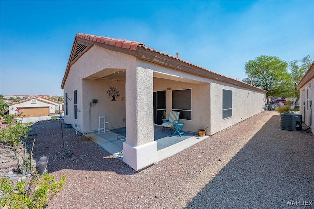 view of side of property featuring a tiled roof, a patio area, central AC unit, and stucco siding