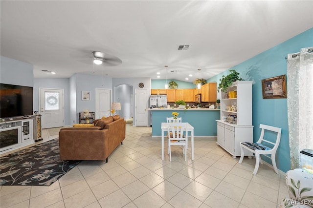 living area featuring arched walkways, light tile patterned floors, lofted ceiling, visible vents, and a ceiling fan