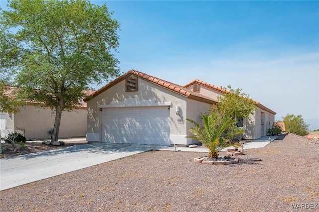 mediterranean / spanish home with a garage, a tiled roof, concrete driveway, and stucco siding