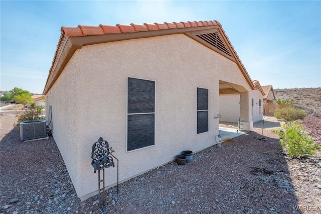 view of property exterior with a patio, central AC unit, and stucco siding