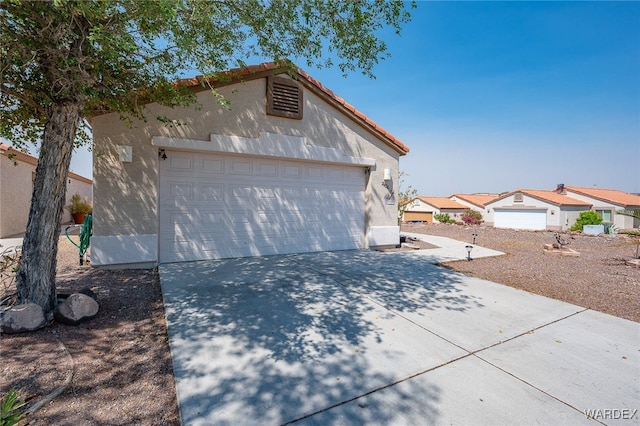 view of front of home featuring a garage, a tiled roof, and stucco siding