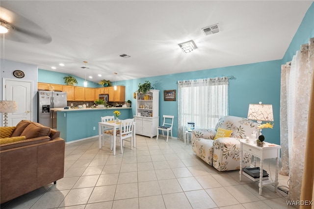 living area with light tile patterned floors, lofted ceiling, and visible vents