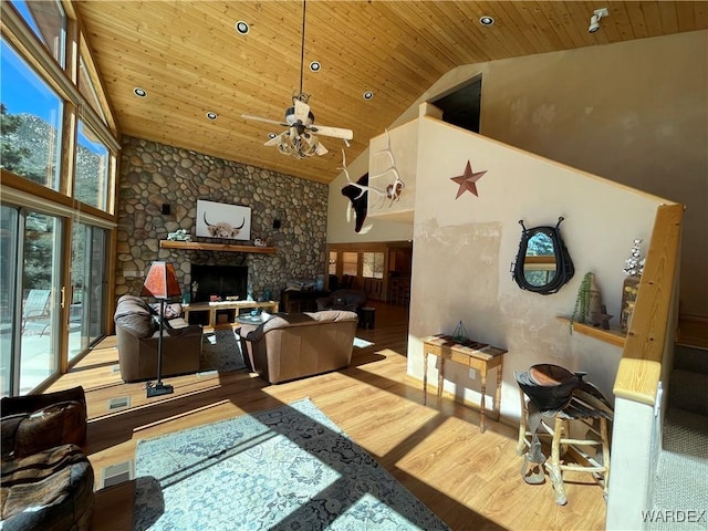 living room with wood ceiling, a wealth of natural light, and a stone fireplace