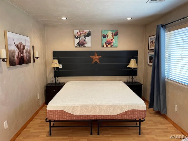 bedroom featuring baseboards, visible vents, and light wood-style floors