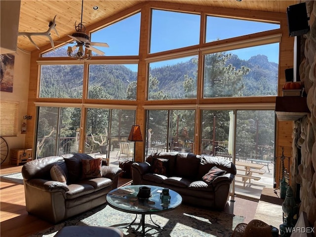 living area with wood ceiling, high vaulted ceiling, a mountain view, and light wood-style flooring