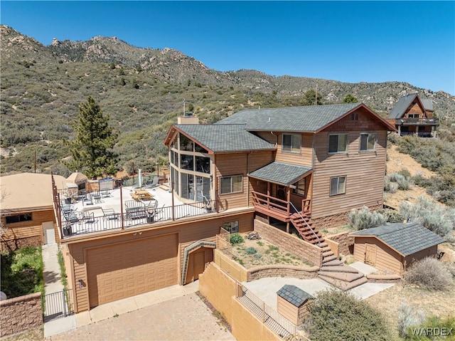 view of front of house with a mountain view, a chimney, an attached garage, and fence