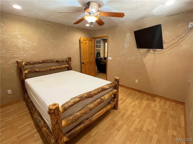 bedroom featuring baseboards, ceiling fan, a textured wall, and light wood-style floors