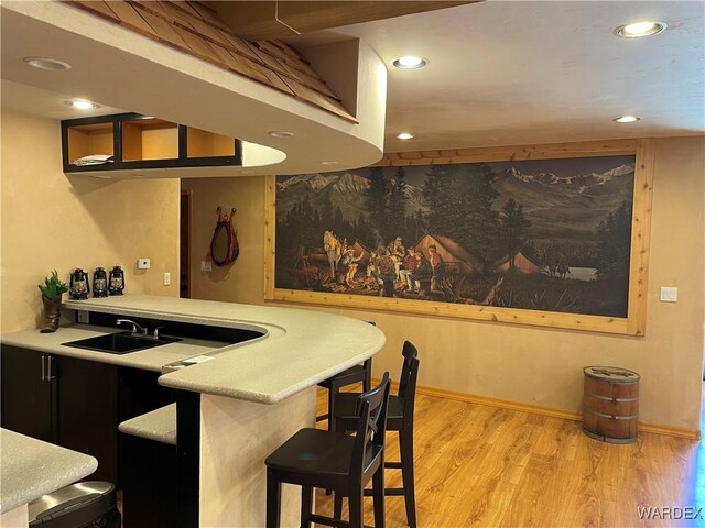 bar with light wood-type flooring, a sink, baseboards, and recessed lighting