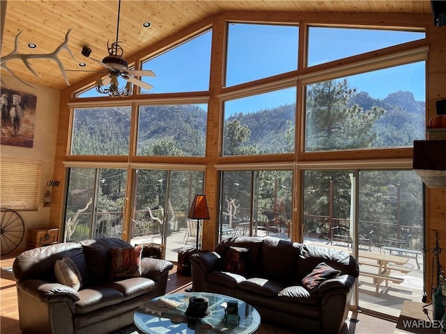 living room with high vaulted ceiling, wood ceiling, a mountain view, and a ceiling fan