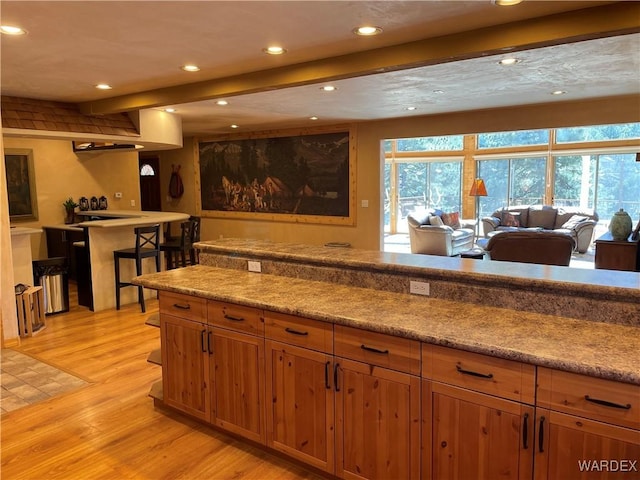 kitchen with recessed lighting, light wood-style floors, open floor plan, beam ceiling, and brown cabinetry