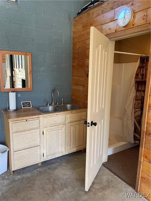 bathroom featuring a stall shower, vanity, concrete block wall, and unfinished concrete floors