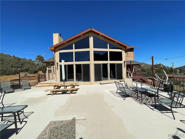 rear view of property with a patio area, a chimney, and fence