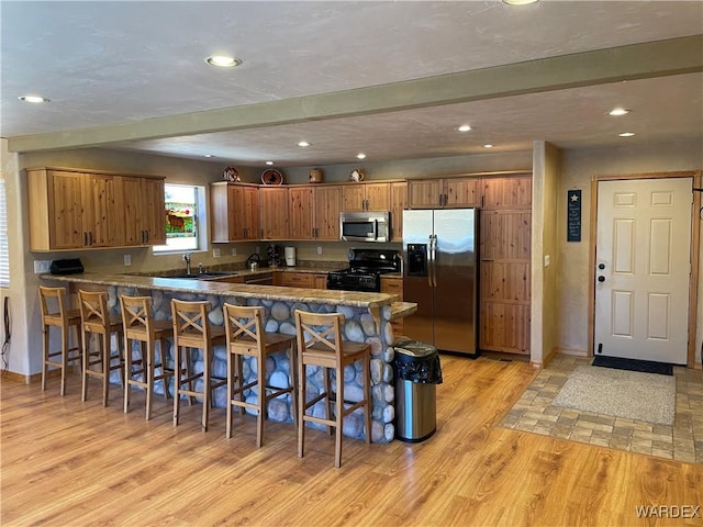 kitchen with dark countertops, brown cabinetry, a peninsula, and stainless steel appliances