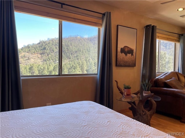 bedroom featuring a forest view, visible vents, and wood finished floors