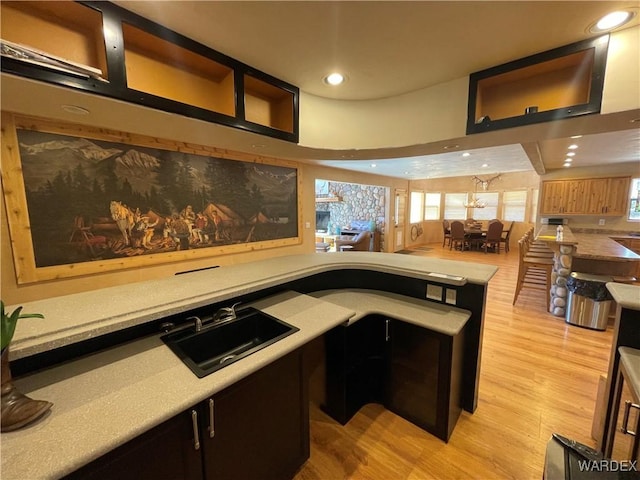 kitchen featuring light wood-style flooring, open floor plan, a peninsula, a sink, and recessed lighting