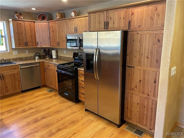 kitchen with visible vents, light wood-style flooring, brown cabinets, stainless steel appliances, and a sink