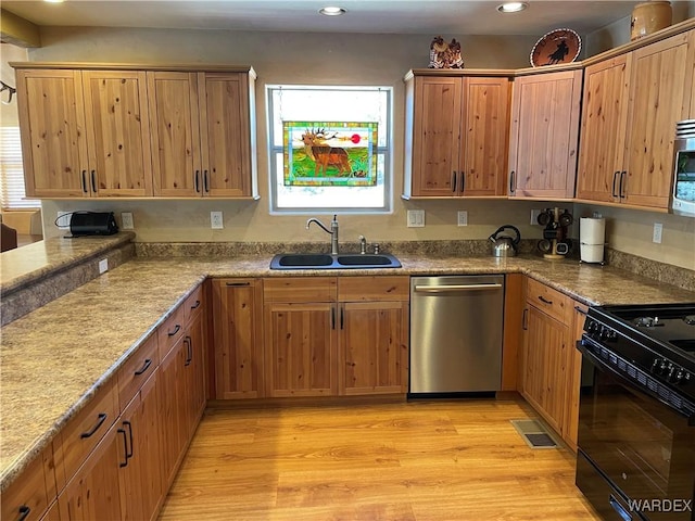 kitchen featuring visible vents, appliances with stainless steel finishes, a sink, light stone countertops, and light wood-type flooring