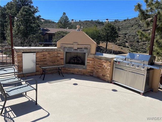 view of patio / terrace featuring exterior fireplace and area for grilling