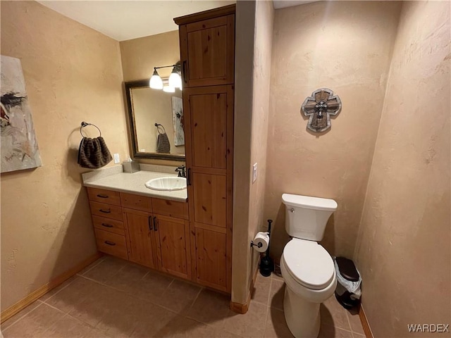 bathroom featuring toilet, tile patterned flooring, baseboards, and vanity