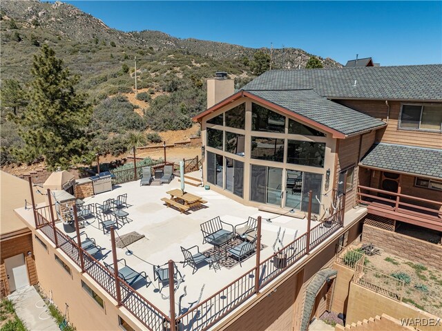 back of property featuring a patio area, a mountain view, and a chimney