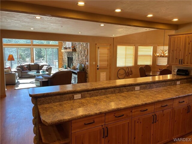 kitchen with a fireplace, recessed lighting, brown cabinetry, open floor plan, and wood finished floors