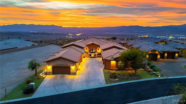 mediterranean / spanish-style house with a garage, driveway, a tile roof, and a mountain view