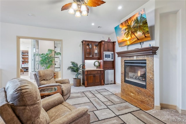 living area with ceiling fan, light carpet, a fireplace, visible vents, and baseboards