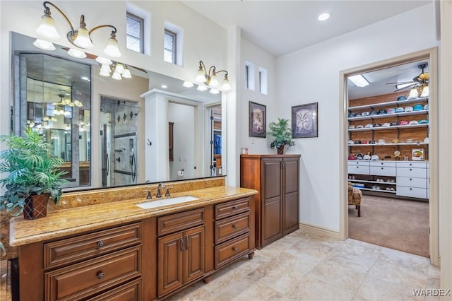 bathroom featuring ceiling fan, a shower stall, vanity, and a walk in closet