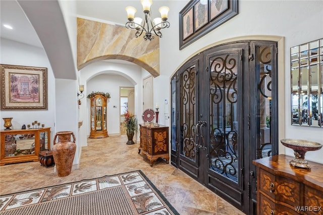 foyer with arched walkways, a chandelier, and french doors