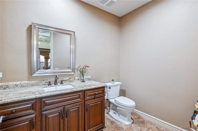 half bath with baseboards, visible vents, vanity, and toilet