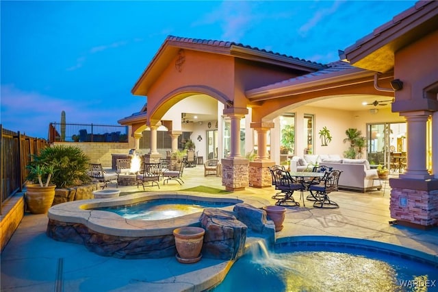 exterior space featuring an in ground hot tub, a patio, fence, and stucco siding