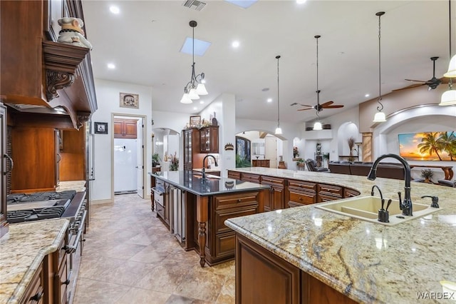 kitchen with stainless steel range, arched walkways, pendant lighting, and a sink