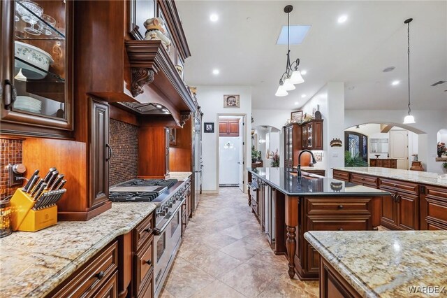 kitchen featuring arched walkways, hanging light fixtures, and double oven range