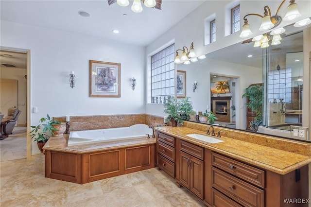 bathroom with a fireplace, a garden tub, and vanity