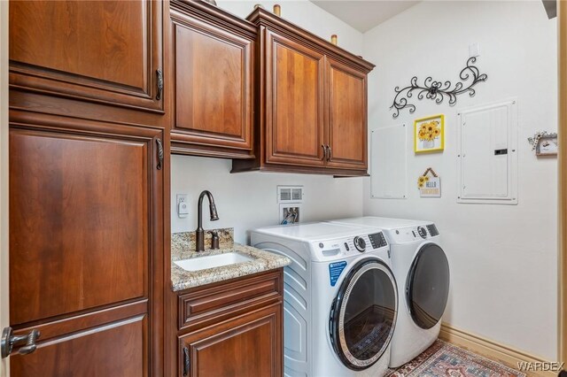 clothes washing area with cabinet space, electric panel, baseboards, separate washer and dryer, and a sink