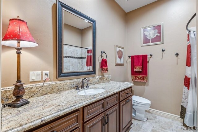 bathroom featuring baseboards, vanity, and toilet