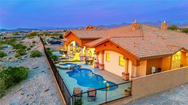 exterior space featuring a pool with connected hot tub, a fenced backyard, a patio, and a mountain view