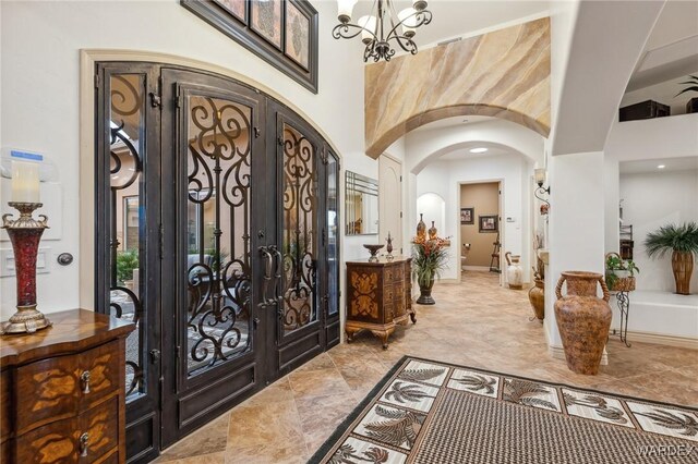 entryway with baseboards, arched walkways, a chandelier, and french doors