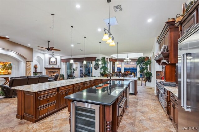 kitchen with wine cooler, visible vents, open floor plan, hanging light fixtures, and a lit fireplace