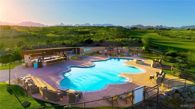 pool featuring a patio area, a mountain view, fence, and outdoor dry bar