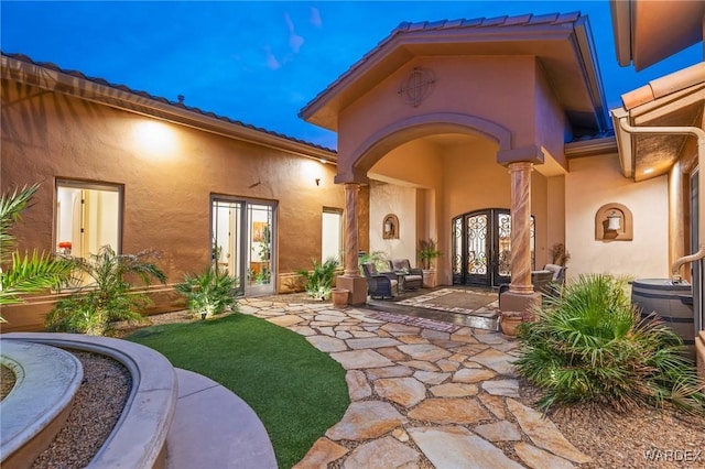 doorway to property featuring a patio, french doors, and stucco siding