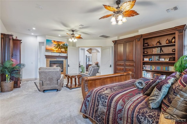 bedroom featuring light colored carpet, a high end fireplace, visible vents, and arched walkways