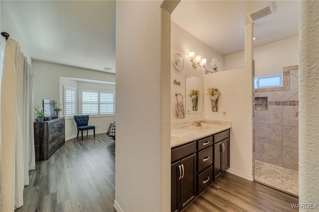 bathroom with baseboards, visible vents, wood finished floors, walk in shower, and vanity