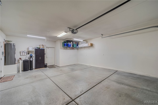 garage featuring baseboards, electric water heater, and a garage door opener