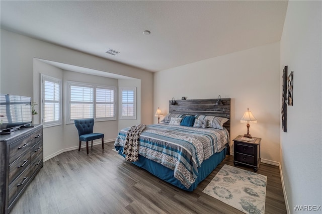 bedroom with wood finished floors, visible vents, and baseboards