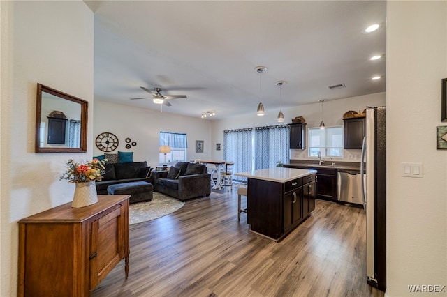 kitchen with a center island, stainless steel appliances, light countertops, hanging light fixtures, and open floor plan